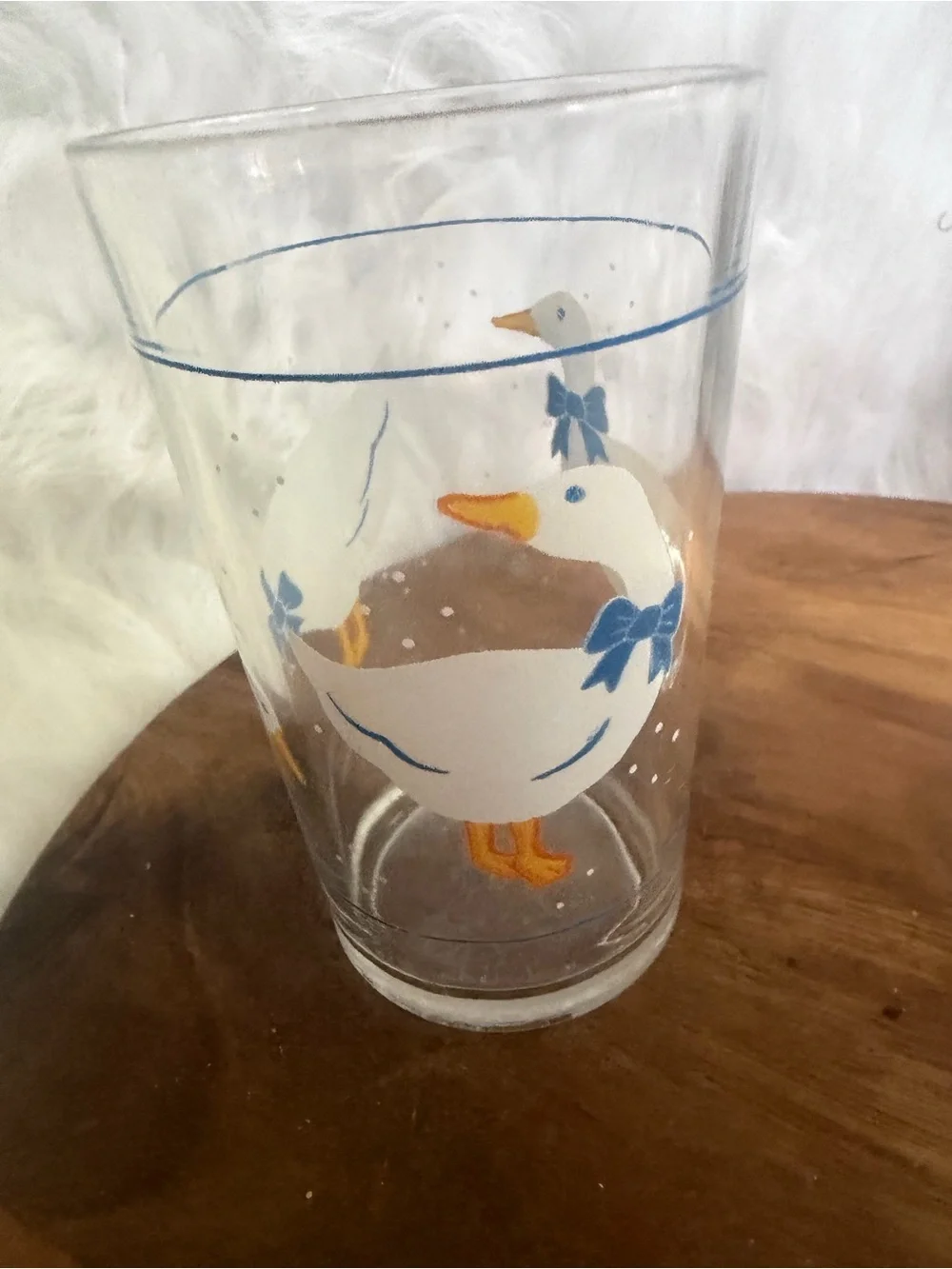 A pair of vintage clear glass tumblers with white geese and blue bows.